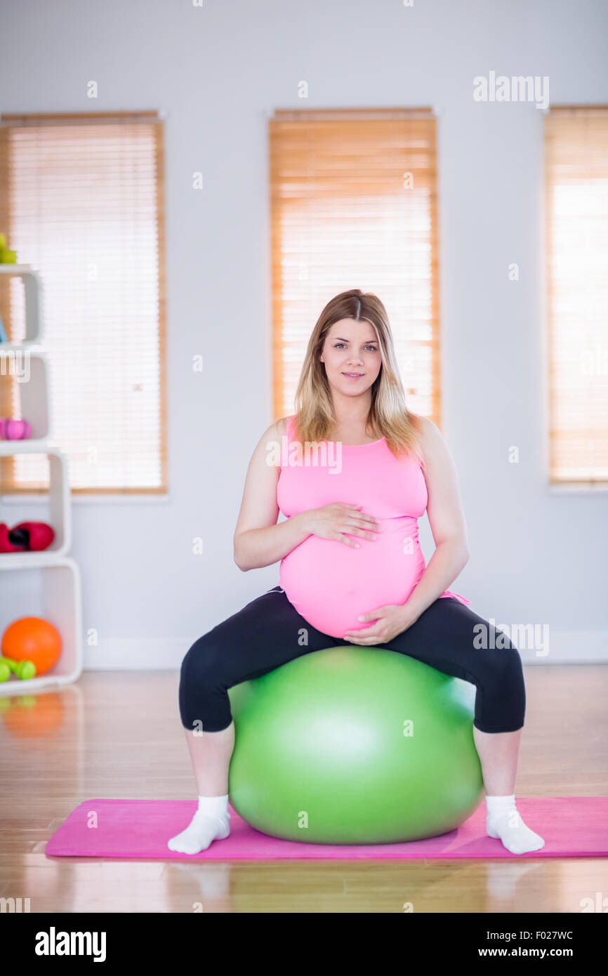 Pregnant woman looking at camera sitting on exercise ball Stock Photo ...