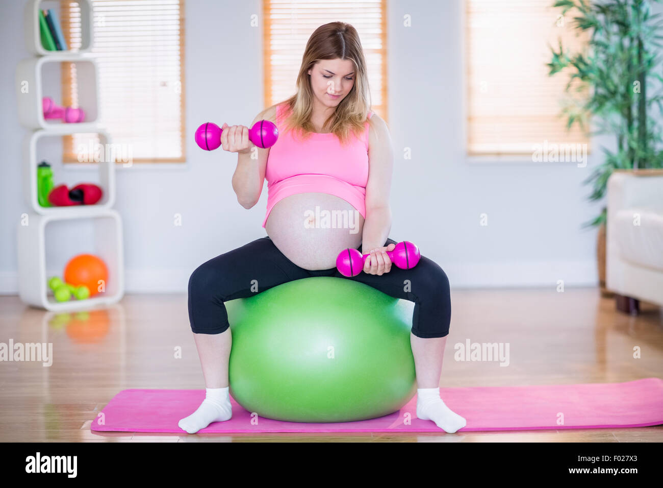 Pregnant woman lifting dumbbells on exercise ball Stock Photo Alamy