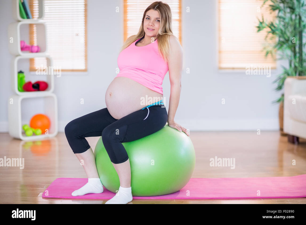 Pregnant woman looking at camera sitting on exercise ball Stock Photo ...