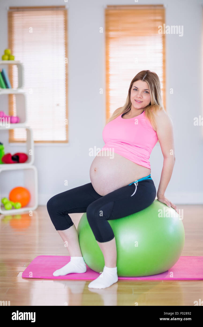 Pregnant woman looking at camera sitting on exercise ball Stock Photo ...