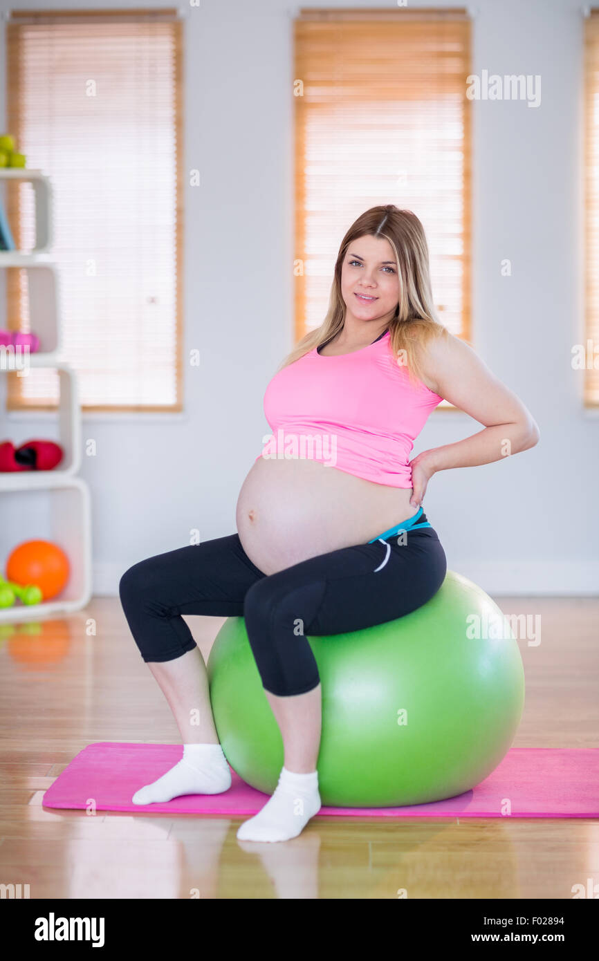 Pregnant woman looking at camera sitting on exercise ball Stock Photo