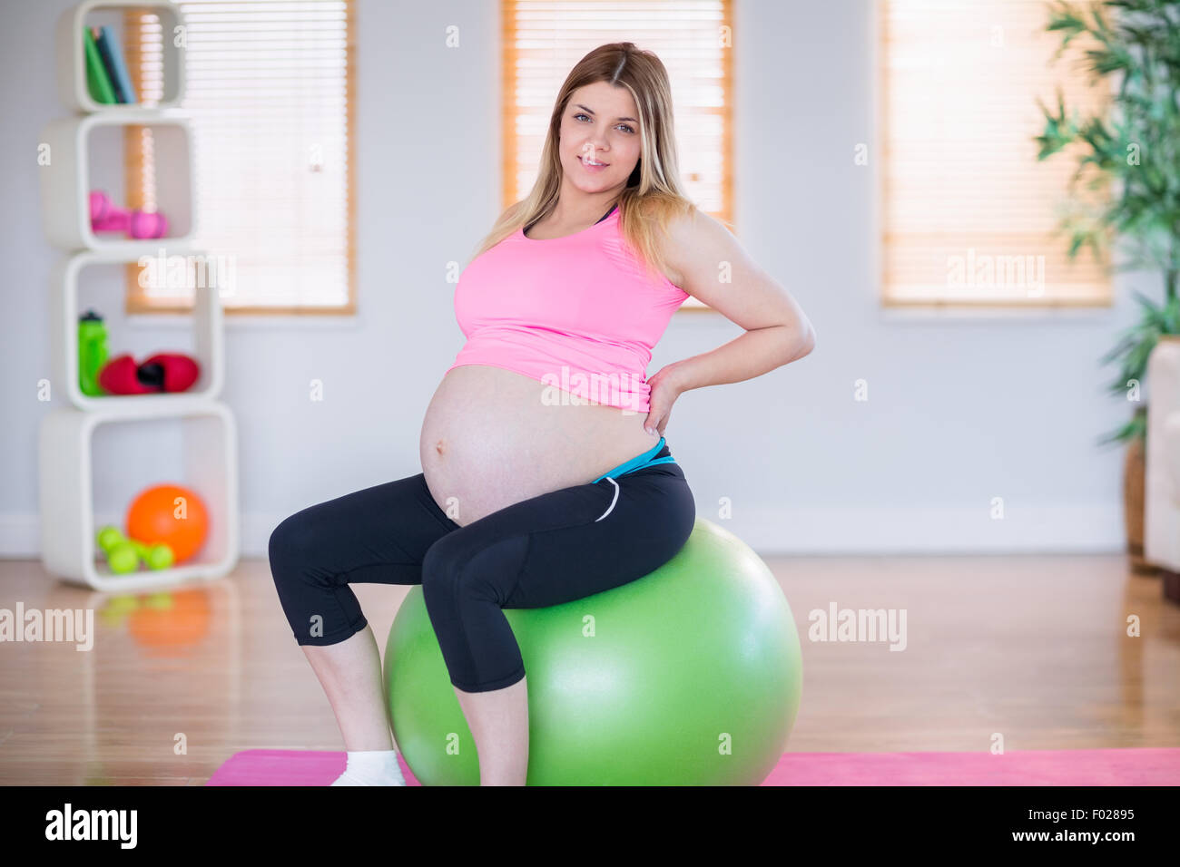 Pregnant woman looking at camera sitting on exercise ball Stock Photo ...
