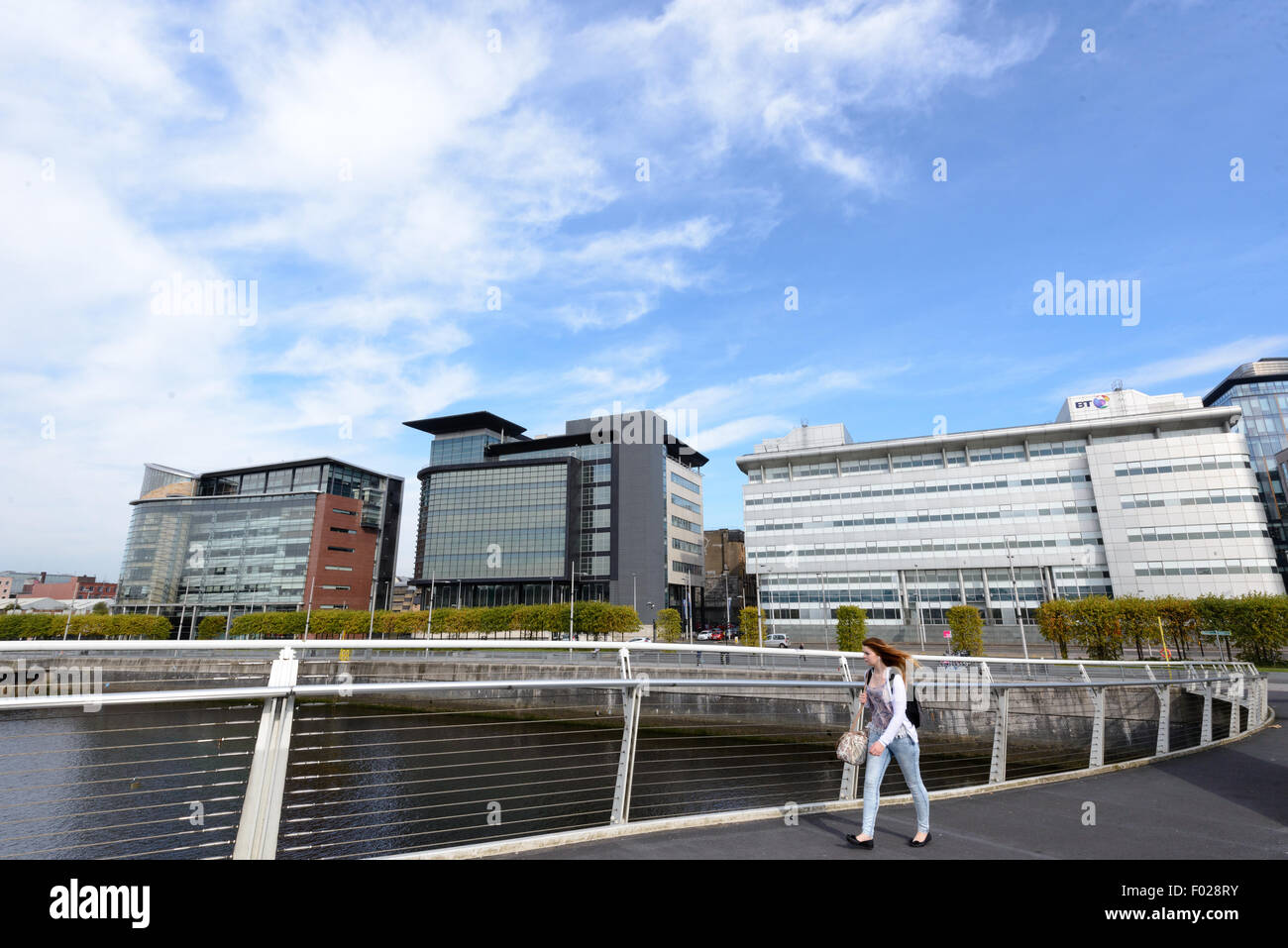 A woman walks across the river Clyde in Glasgow on the Broomielaw-Tradeston Bridge (known locally as the Squiggly Bridge). Stock Photo