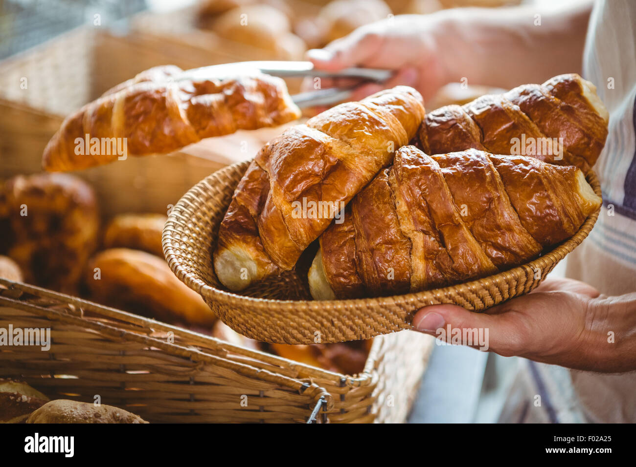 happy worker holding a basket of croissant Stock Photo