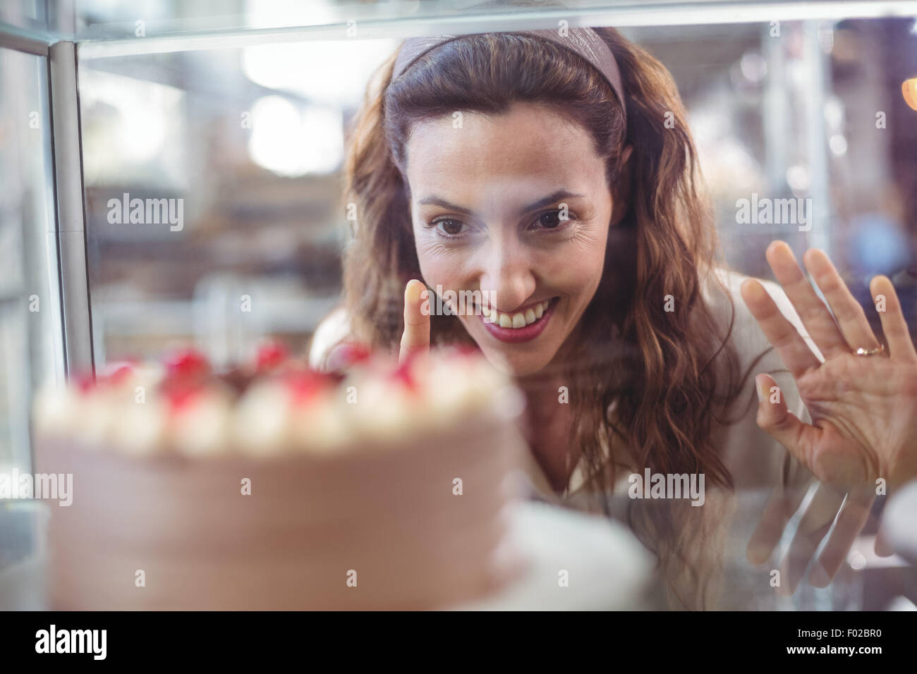 Pretty Brunette Looking At Chocolate Cake Through The Glass Stock