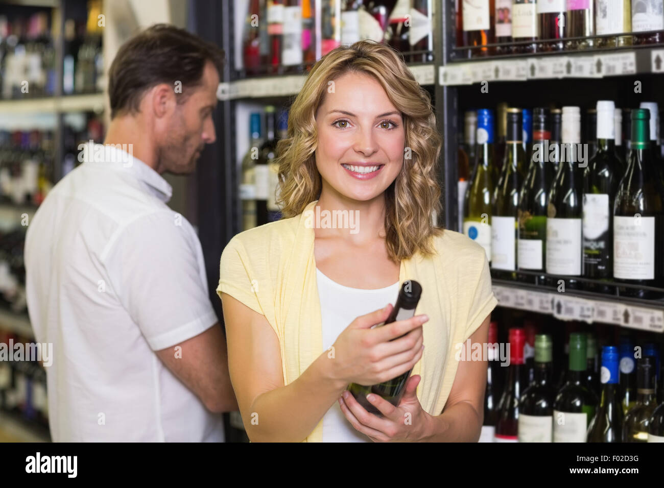 Portrait of smiling pretty blonde woman looking at wine bottle Stock ...