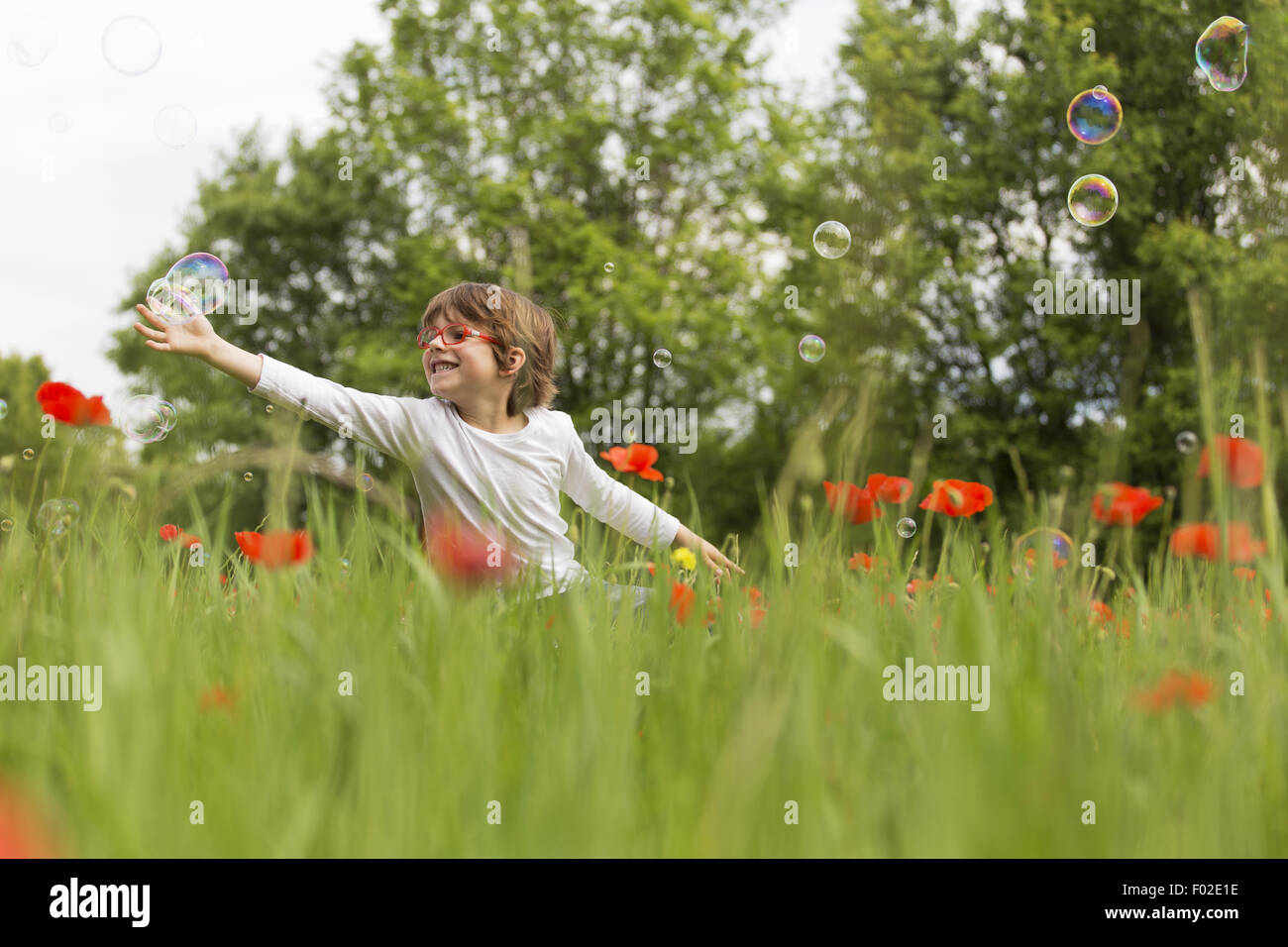 Boy playing with soap bubbles in a poppy field Stock Photo - Alamy