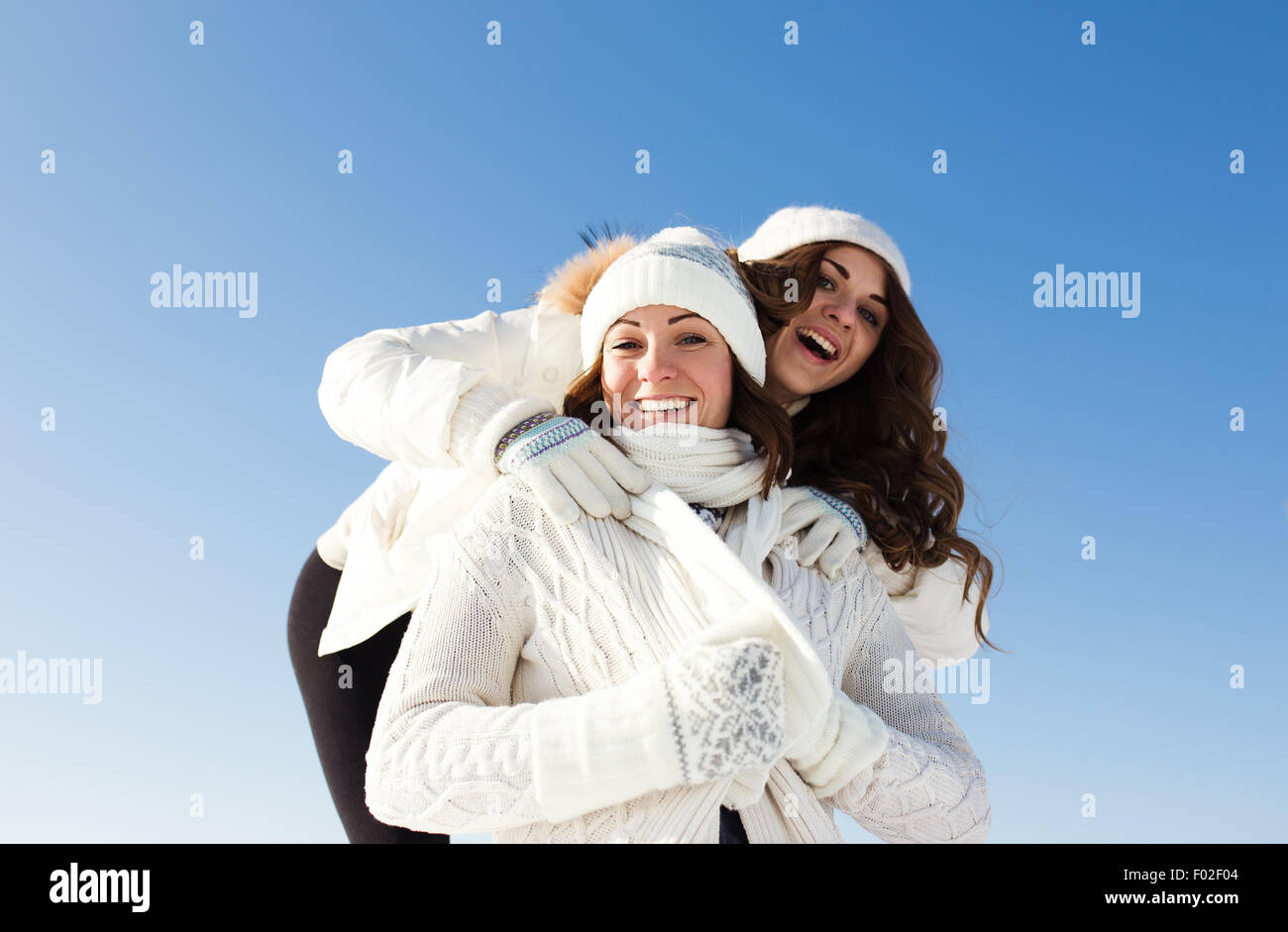 Two girlfriends have fun and enjoy fresh snow at beautiful winter day Stock Photo