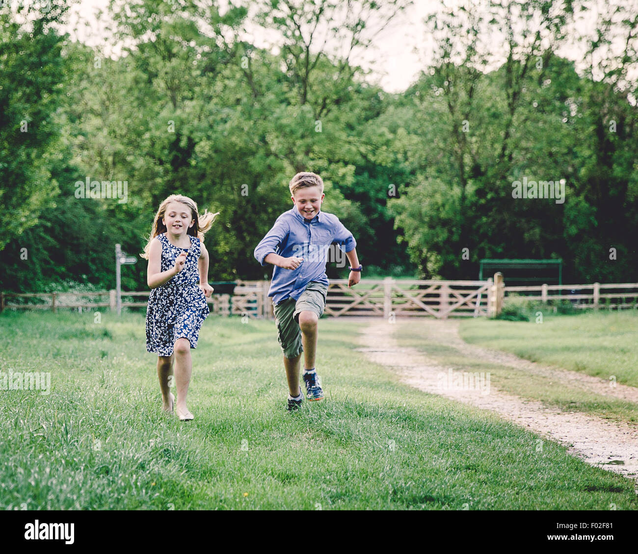 Two children racing each other in a field Stock Photo