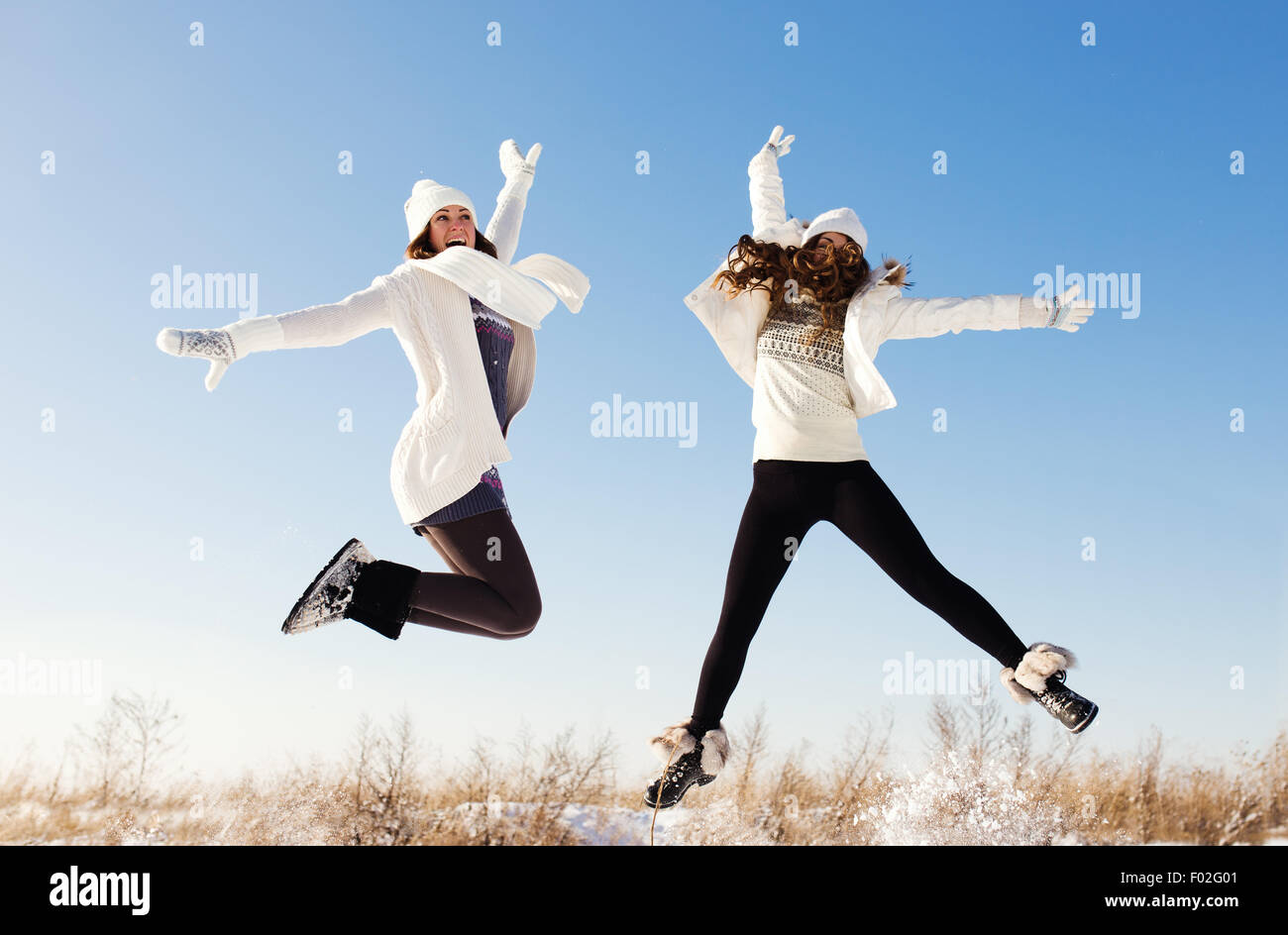 Two girlfriends have fun and enjoy fresh snow at beautiful winter day Stock Photo