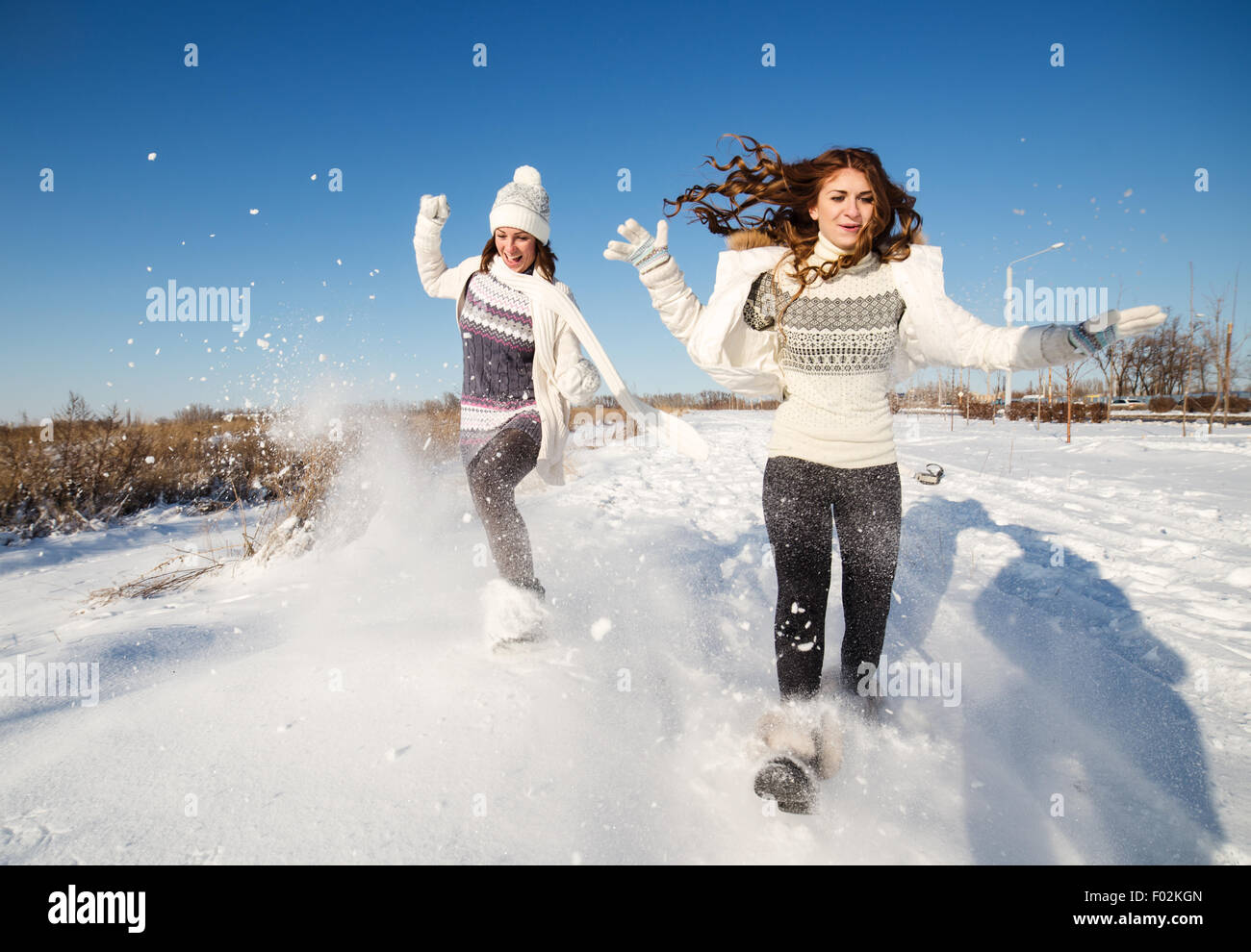 Two girlfriends have fun and enjoy fresh snow at beautiful winter day Stock Photo