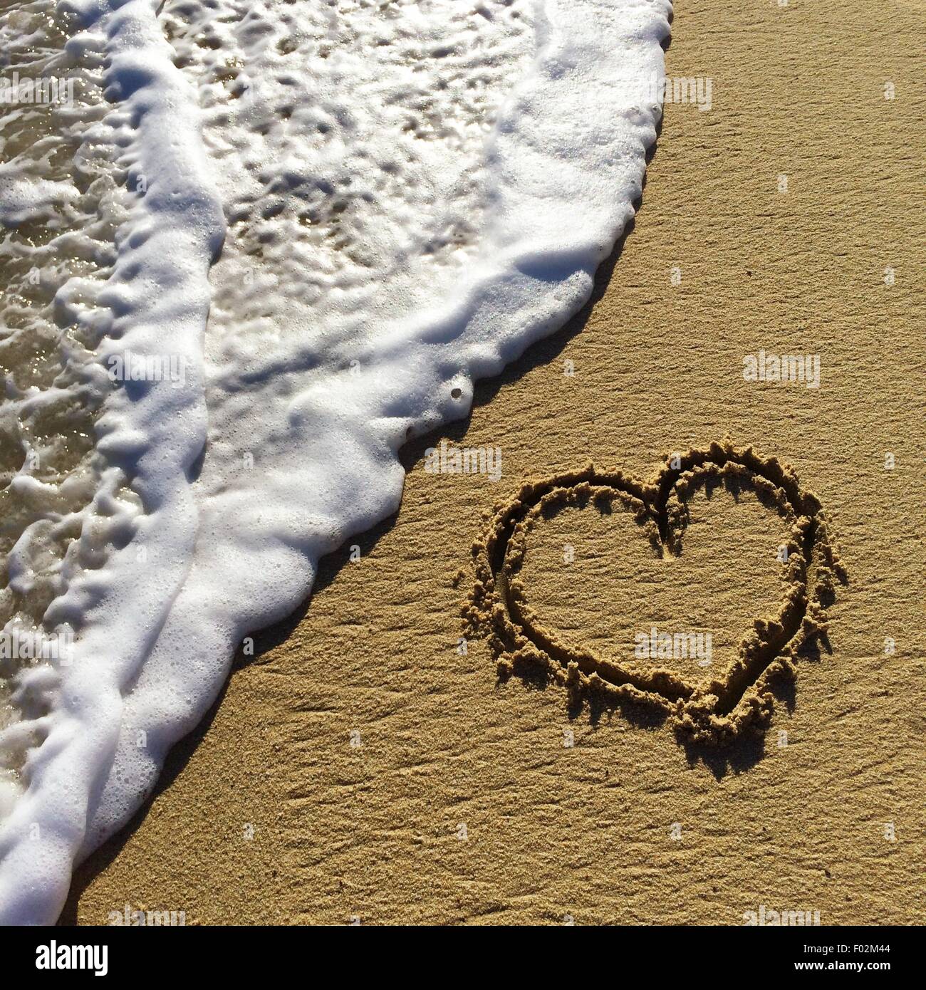 Heart shape drawn in the sand on a beach Stock Photo