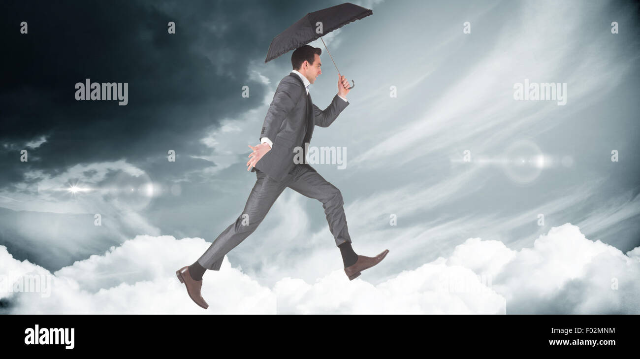 Composite image of businessman jumping holding an umbrella Stock Photo