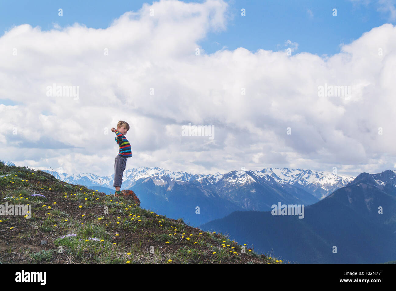 Boy standing on hill with outstretched arms Stock Photo