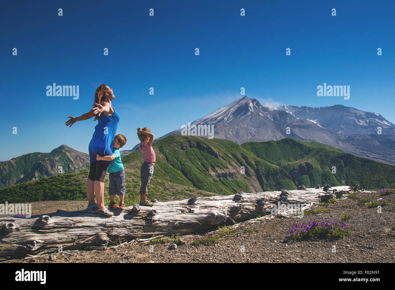 Mother and two children standing on a log Stock Photo