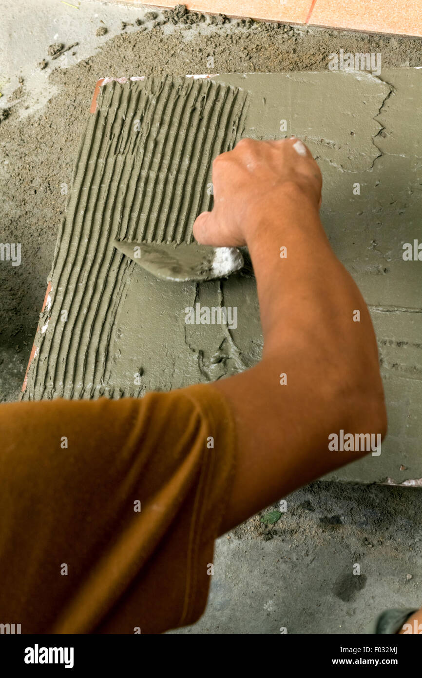 a tiler at work. bonding of floor tile with tile adhesive and filler