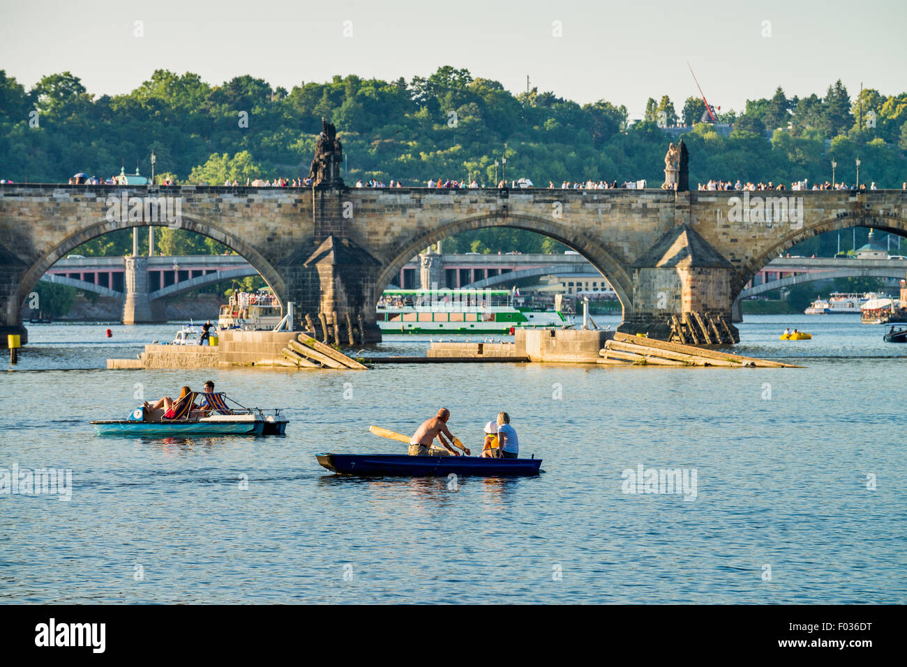 People in carshaped paddle boats in Vltava River with Charles bridge