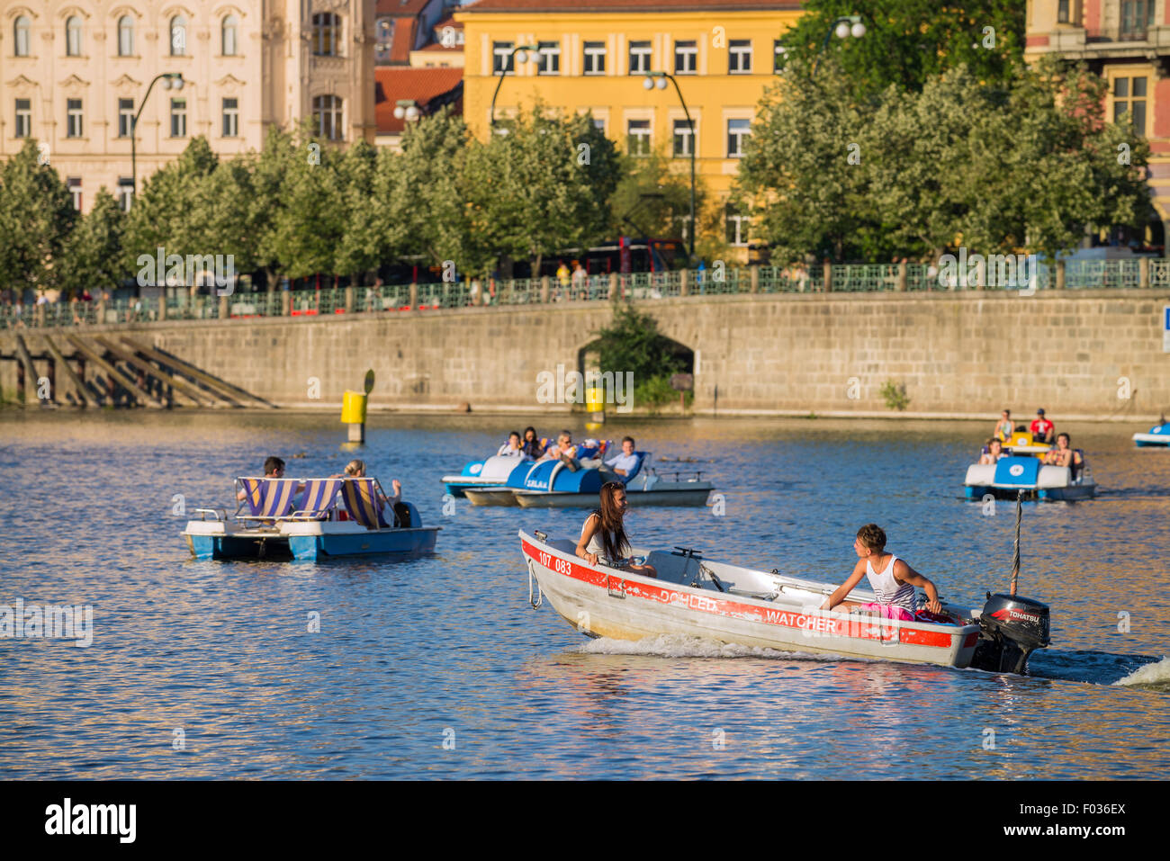People in carshaped paddle boats in Vltava River with Charles bridge