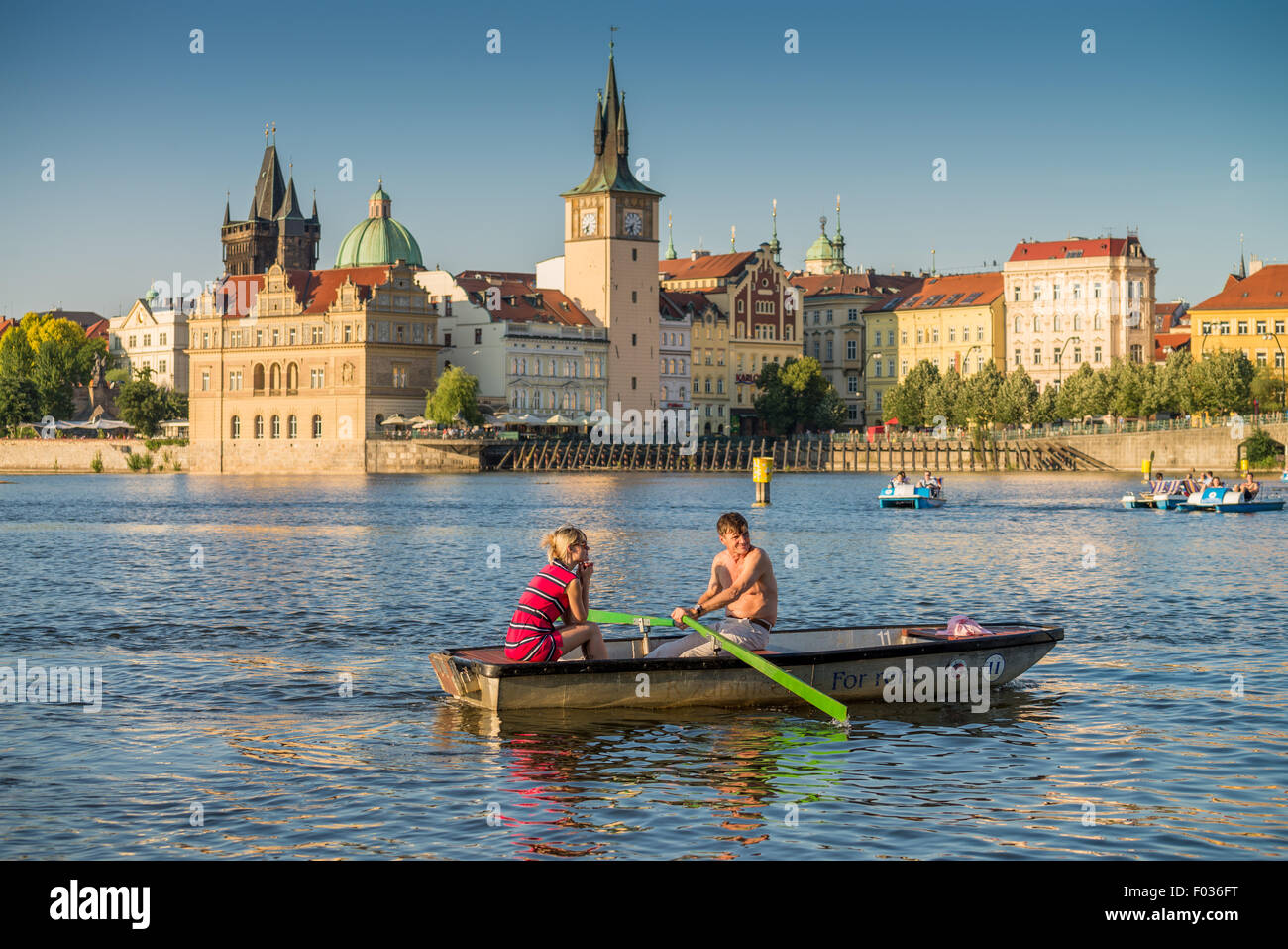 People in carshaped paddle boats in Vltava River with Charles bridge