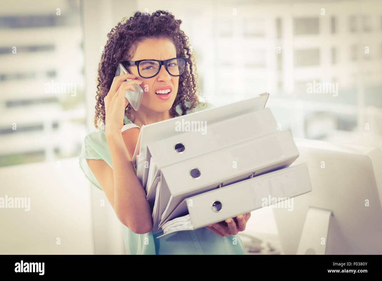 Stunned businesswoman carrying a stack of folders Stock Photo