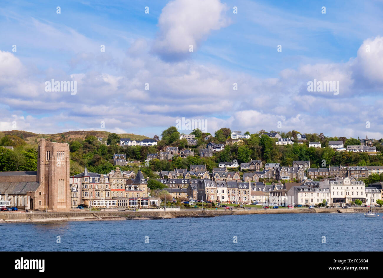 Offshore view across sea to waterfront buildings and St Columba's Cathedral catholic church in Oban Argyll and Bute Scotland UK Stock Photo