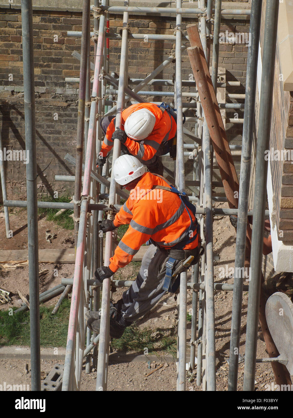 Scaffolders in the process of dismantling a spiders web of steel upon a listed building after renovation work has been completed Stock Photo