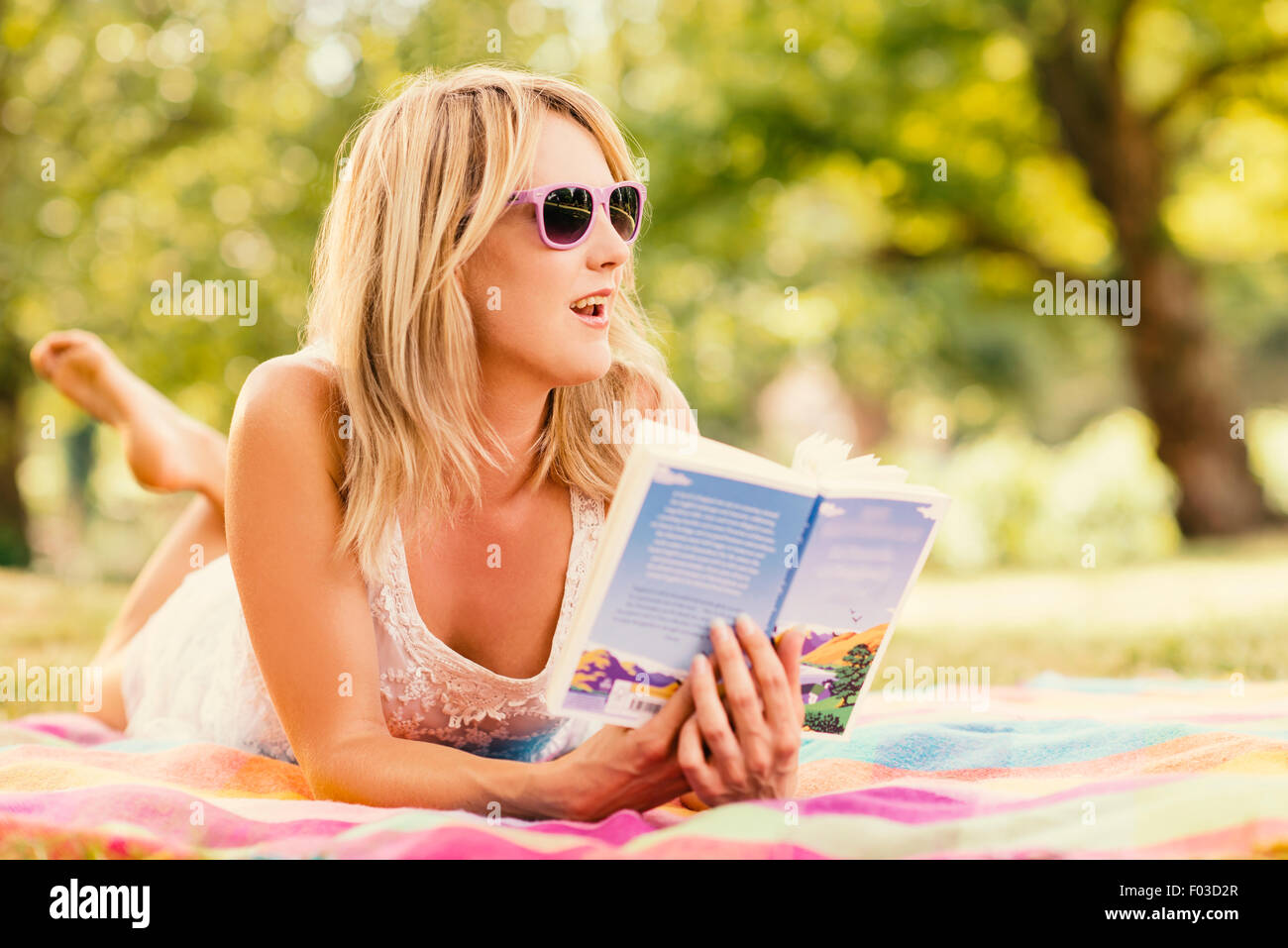 Woman reading on blanket in park Stock Photo