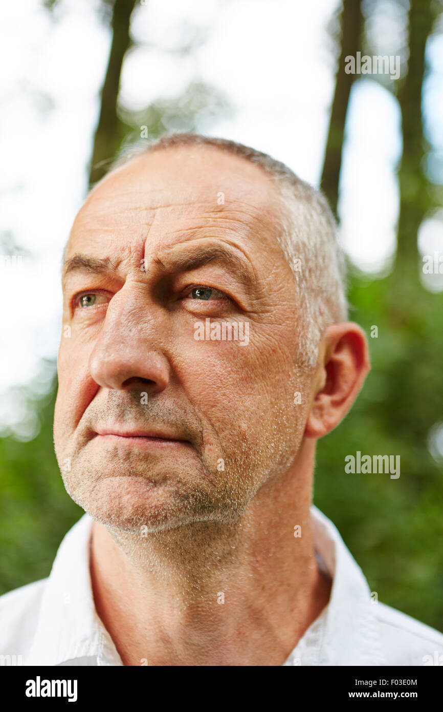 Old man in nature looking seriously outside Stock Photo