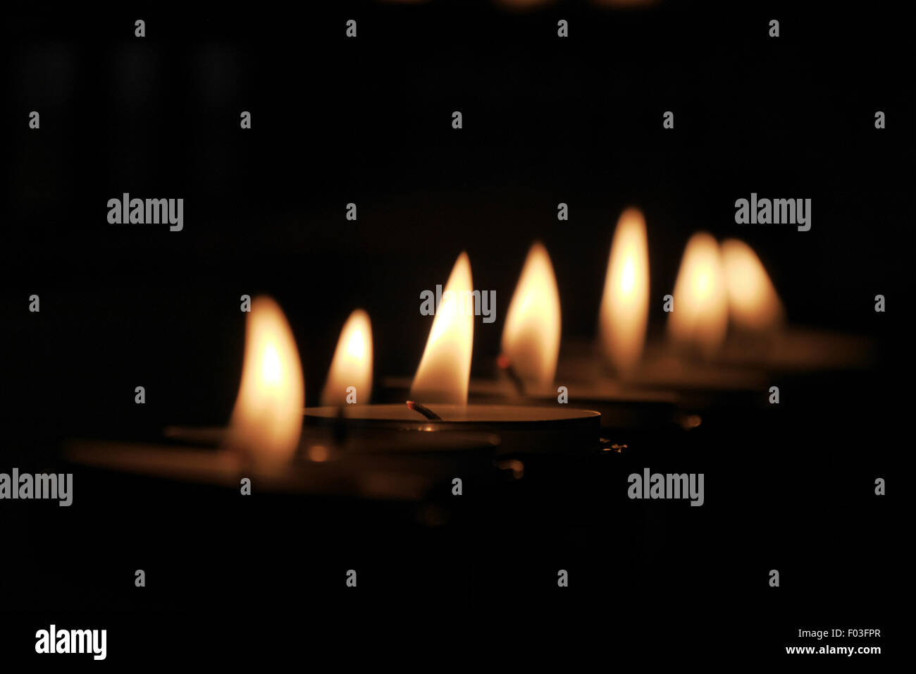 Warm glow of tealight flames burning in the darkness Stock Photo