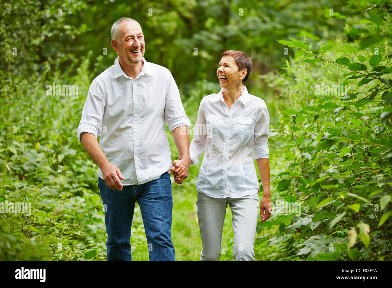 Happy senior couple taking a walk in a forest in summer Stock Photo