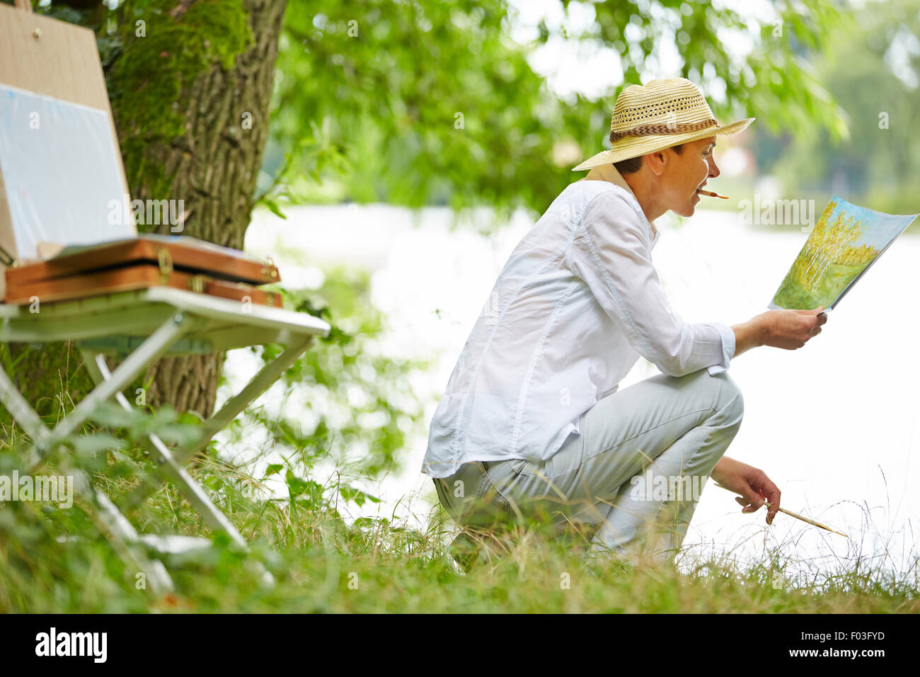 Happy senior woman painting picture in nature in summer Stock Photo