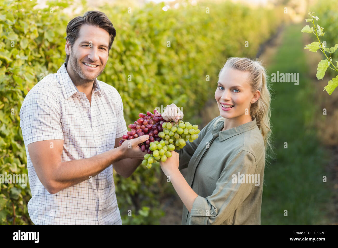 Two young happy vintners holding grapes Stock Photo