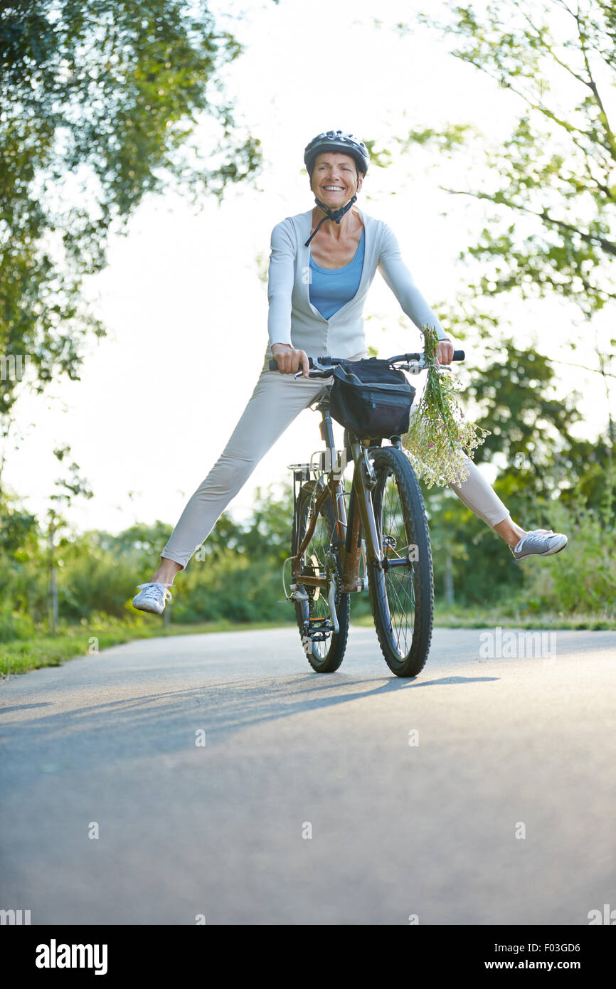 Happy senior woman having fun riding her bike in summer Stock Photo