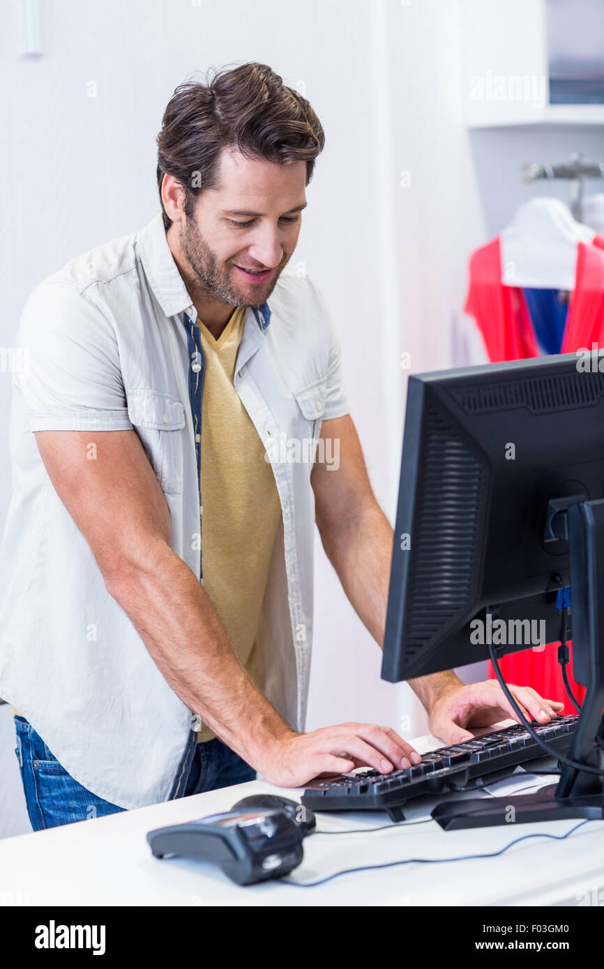 Smiling cashier typing Stock Photo