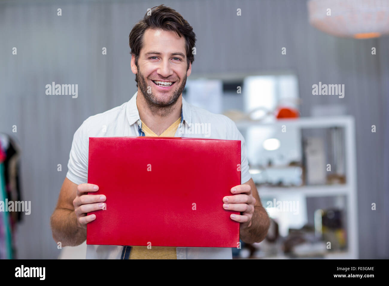 Smiling man holding up red blank sign Stock Photo