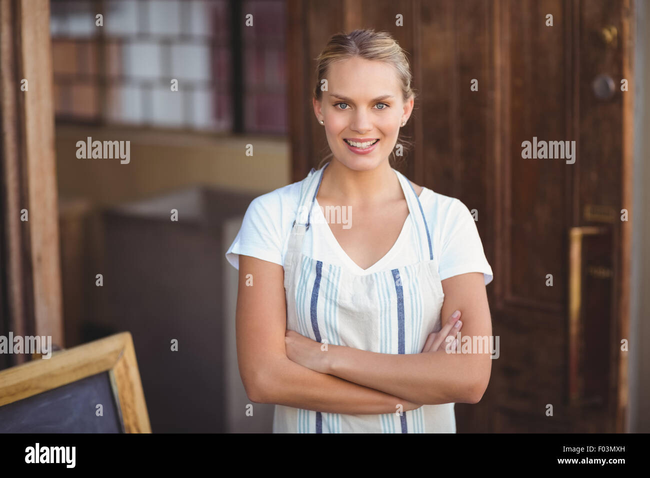 Smiling blonde waitress with arms crossed Stock Photo - Alamy