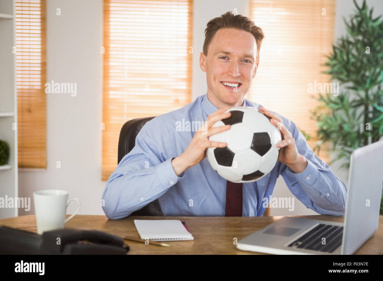 Cheerful businessman holding a soccer ball Stock Photo - Alamy