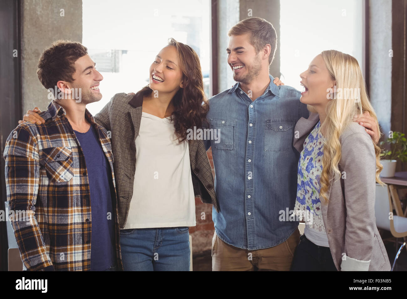 Smiling friends laughing and putting arms around each other Stock Photo
