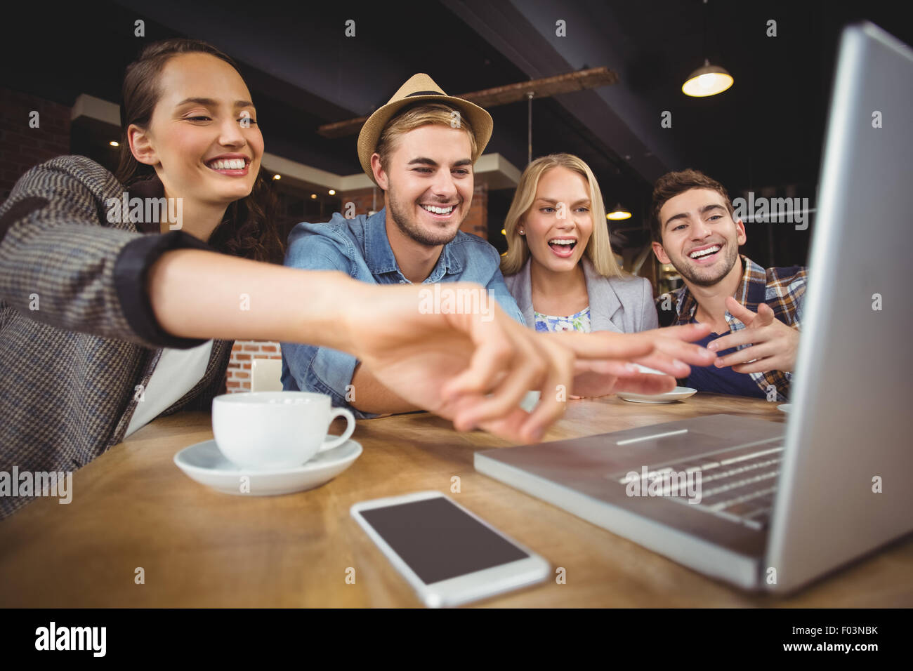 Laughing friends looking at laptop and pointing at screen Stock Photo