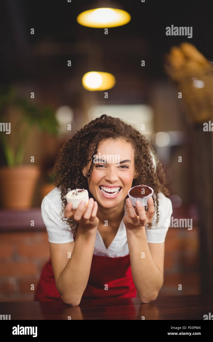 Laughing waitress showing two cupcakes Stock Photo