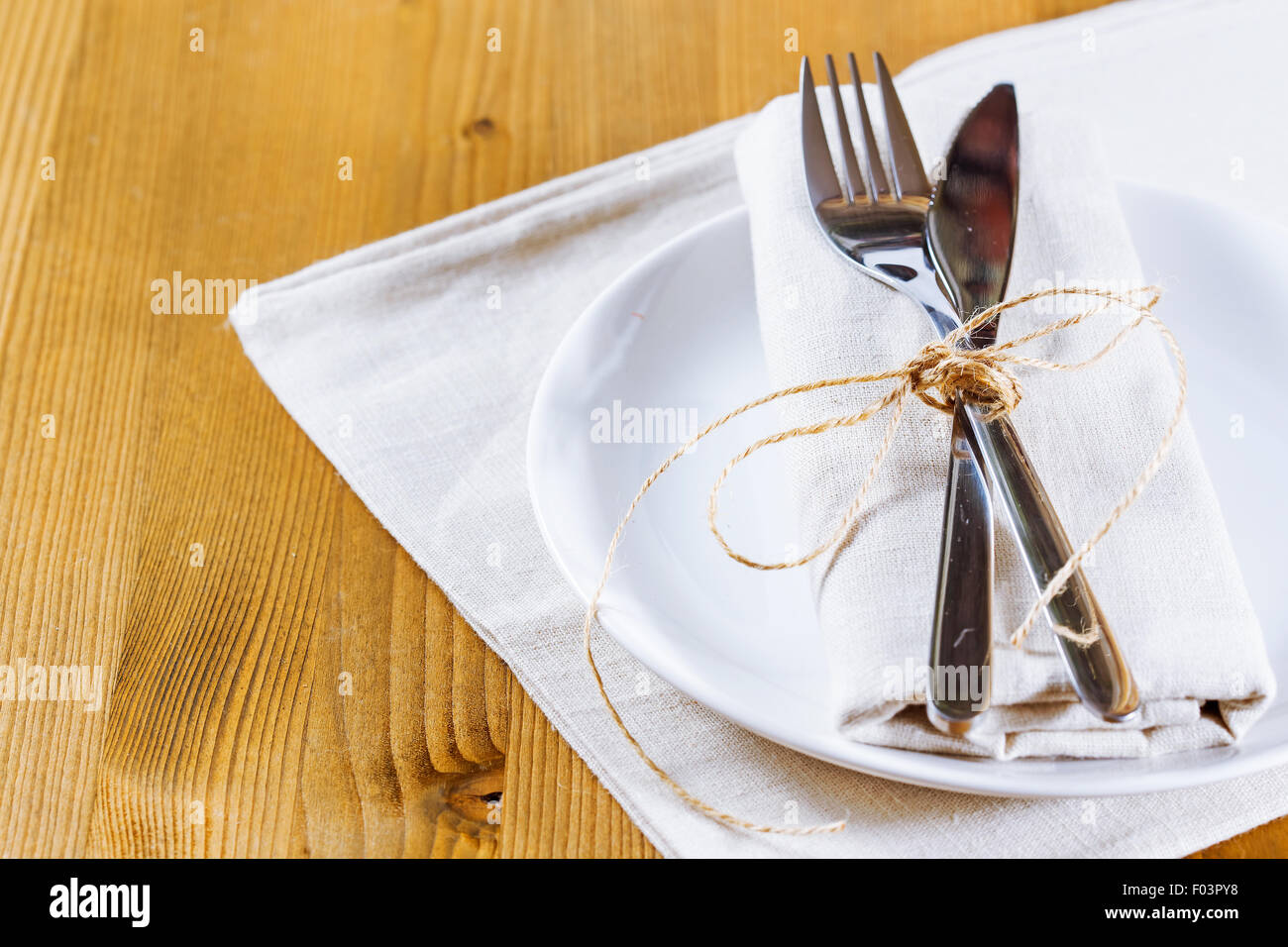 Autumn place setting. Knife and fork with white linen tied up with ...
