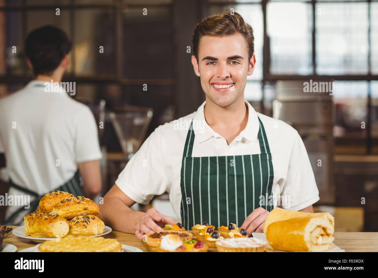 Smiling waiter tidying up the pastries Stock Photo
