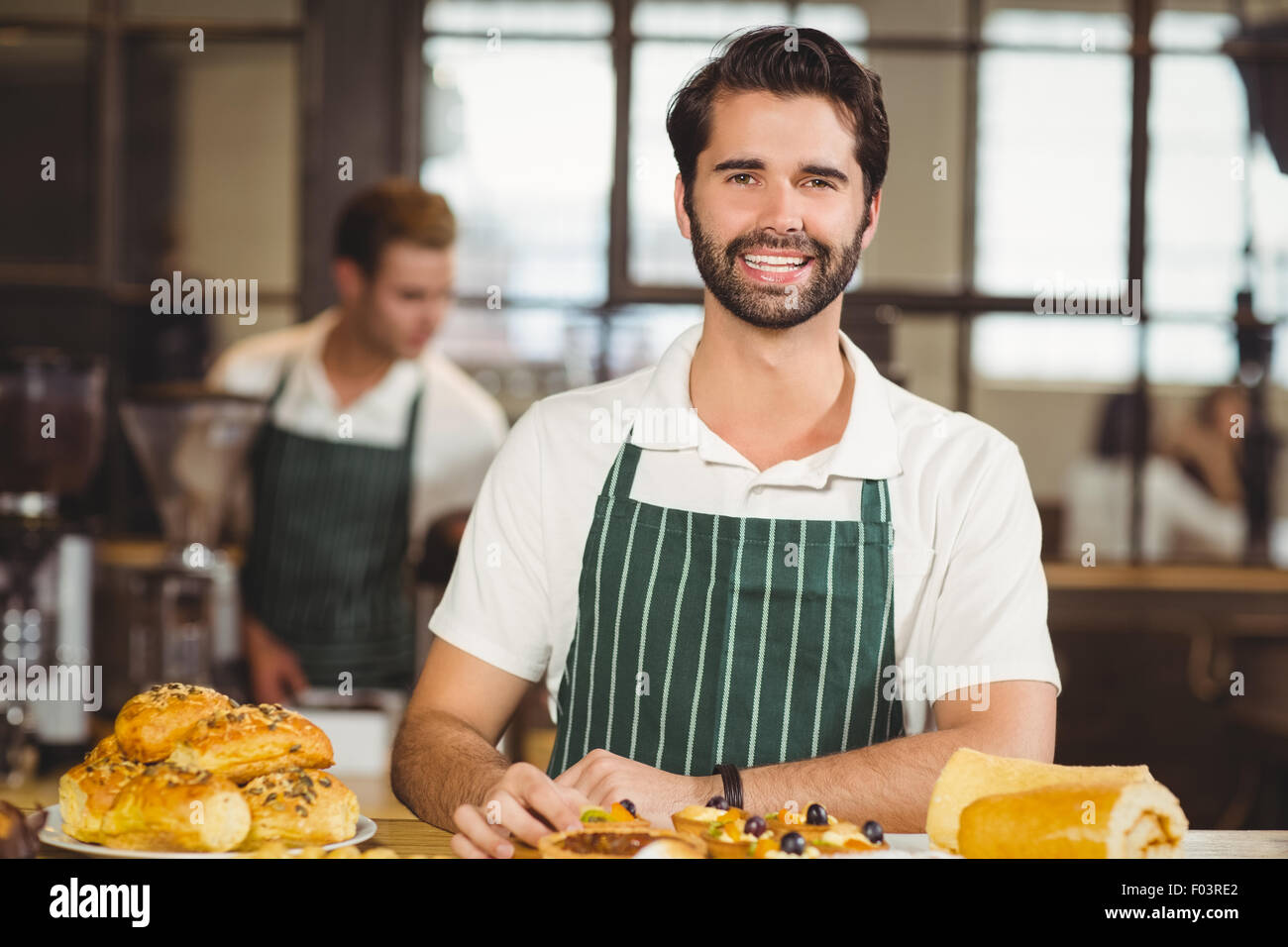 Smiling waiter tidying up the pastries Stock Photo