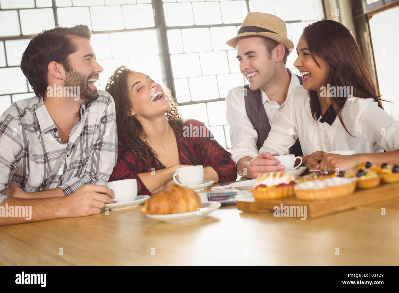 Laughing friends enjoying coffee and treats Stock Photo