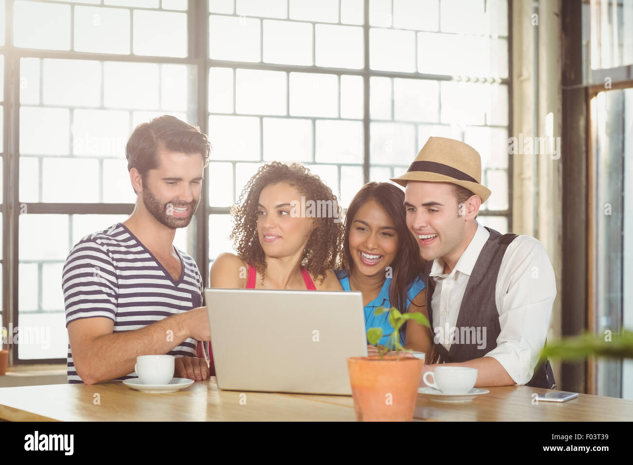 Smiling friends looking at laptop and having coffee Stock Photo