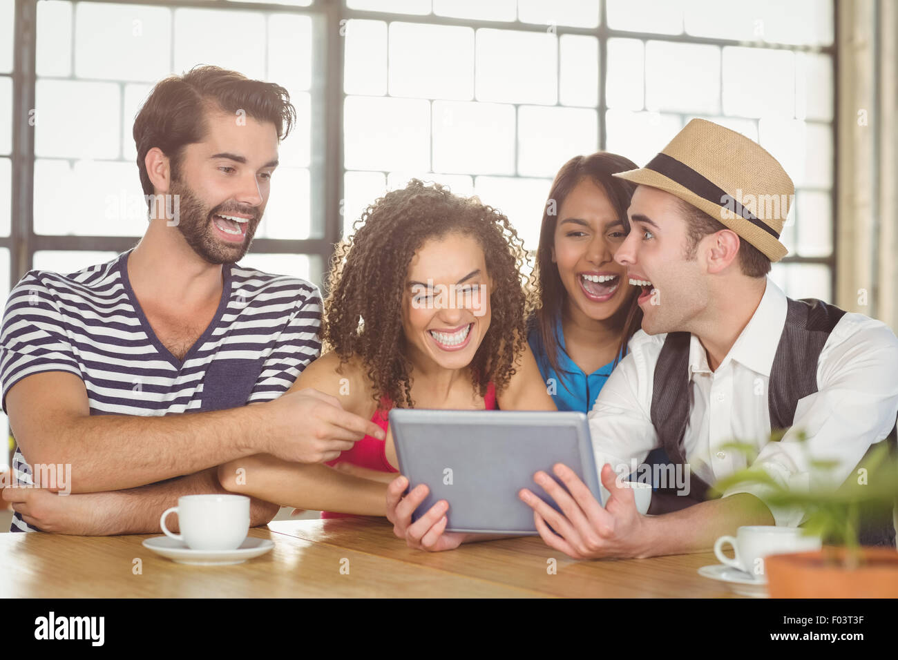 Happy friends laughing while looking at tablet Stock Photo