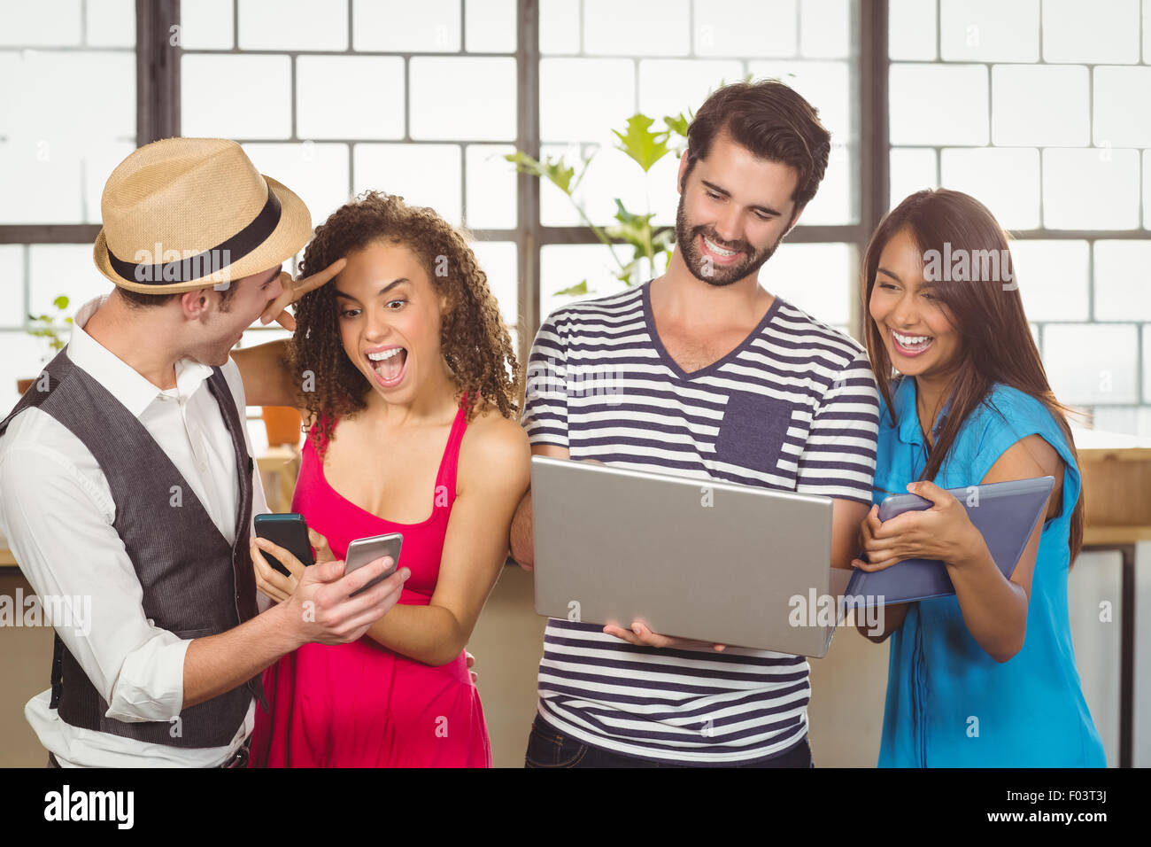 Laughing friends using different types of multimedia Stock Photo