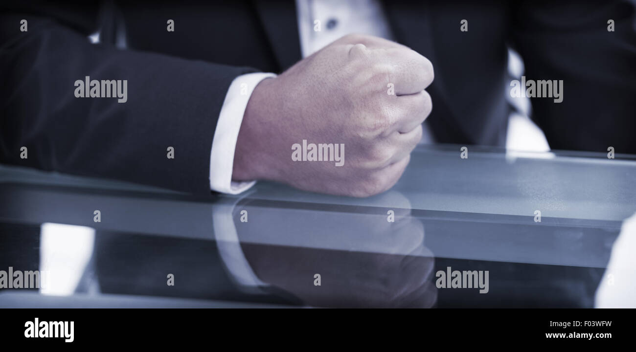 Mid section of businessman with clenched fist on office desk Stock Photo