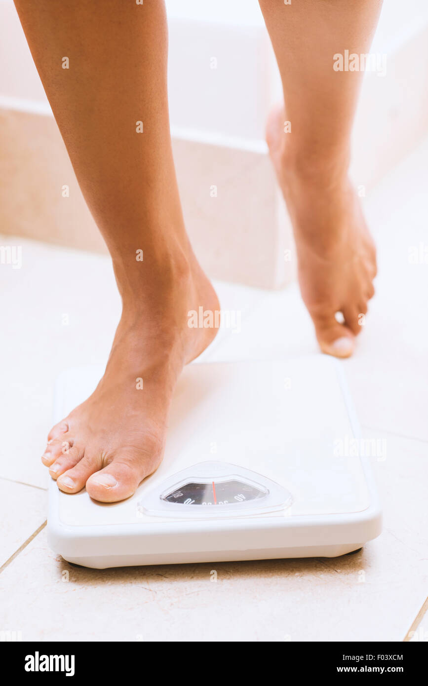 Woman weighing herself barefoot on bathroom scales Stock Photo