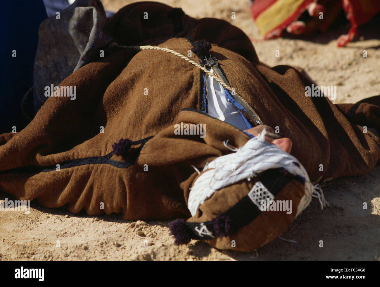 A man in traditional clothes lying on the ground, Matmata Berber festival, Tunisia. Stock Photo